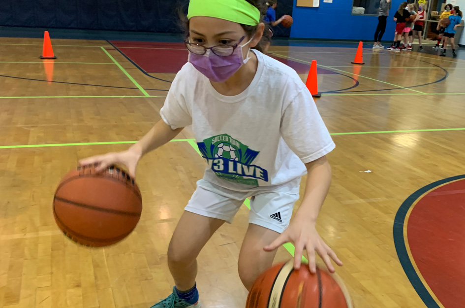 Young girl dribbling 2 basketballs